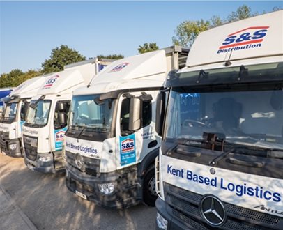 Fleet of S&S Distribution lorries lined up outdoors, each displaying “Kent Based Logistics” on the front and company branding on the doors.