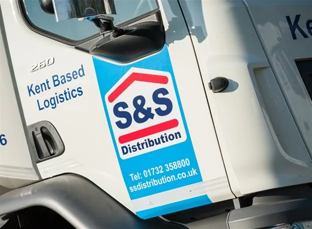 Close-up of an S&S Distribution lorry door with blue branding, the company’s logo, contact number, and website address, showing it is a Kent-based logistics provider.