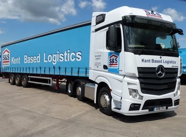 S&S Distribution articulated lorry featuring a large blue curtain side trailer with “Kent Based Logistics” prominently displayed, parked in an industrial yard.